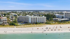 A coastal hotel with multiple floors, a beach in the foreground, and a view of the city in the distance. - Salt Air, Pool @ Sunset Vistas in Treasure Island (Treasure Island)