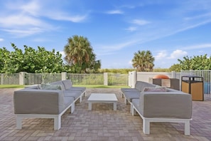 An outdoor patio with a sofa set, a coffee table, and a trash bin. - Salt Air, Pool @ Sunset Vistas in Treasure Island (Treasure Island)