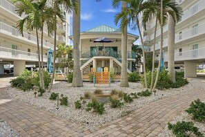 A hotel with a central atrium, palm trees, and a children's play area. - Salt Air, Pool @ Sunset Vistas in Treasure Island (Treasure Island)