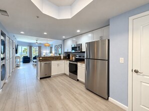 A modern kitchen with stainless steel appliances, white cabinetry, and a light wood floor. - Salt Air, Pool @ Sunset Vistas in Treasure Island (Treasure Island)