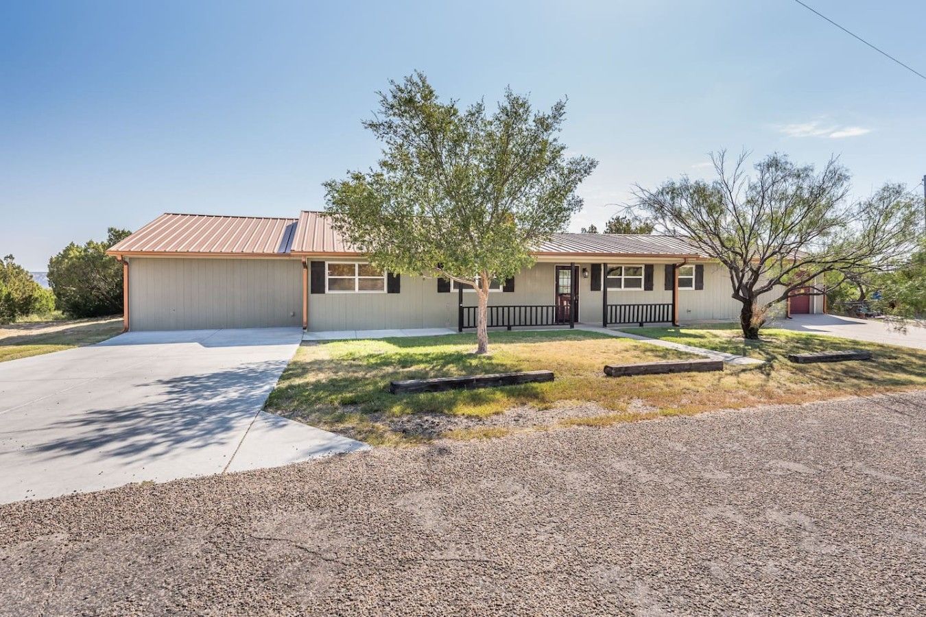 A single-story building with a garage, a covered patio, and a small lawn area.