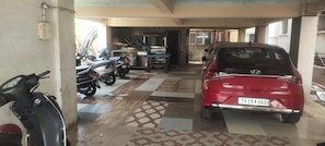 Un área de estacionamiento con un coche rojo y varias motocicletas.