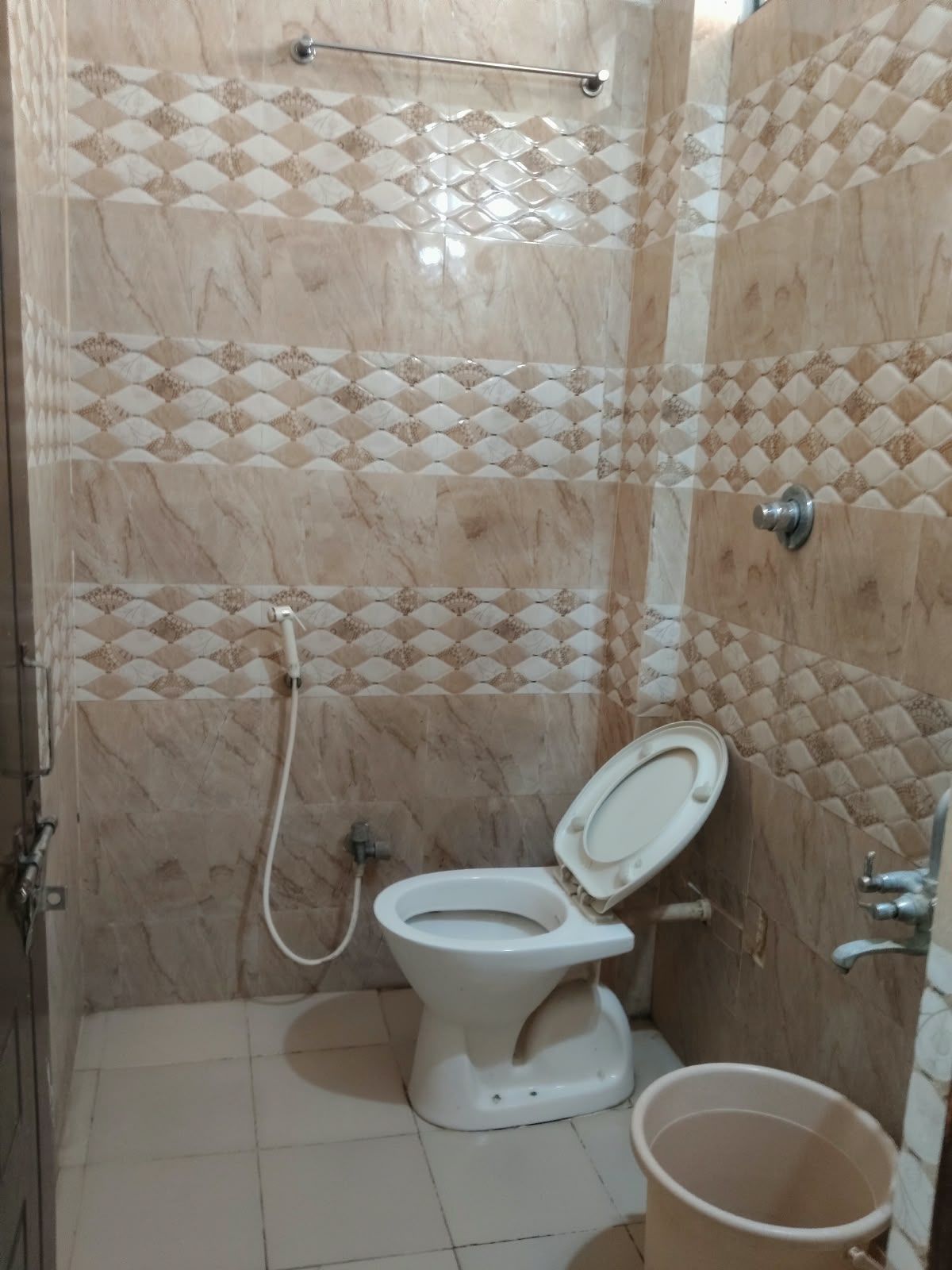 Un baño con inodoro, ducha y barra de apoyo.