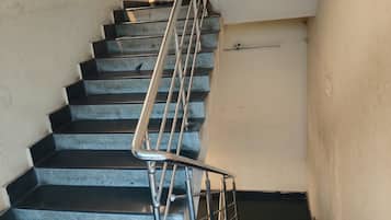 Una escalera con barandas metálicas y una baranda en el lado izquierdo, que conduce a un piso superior.