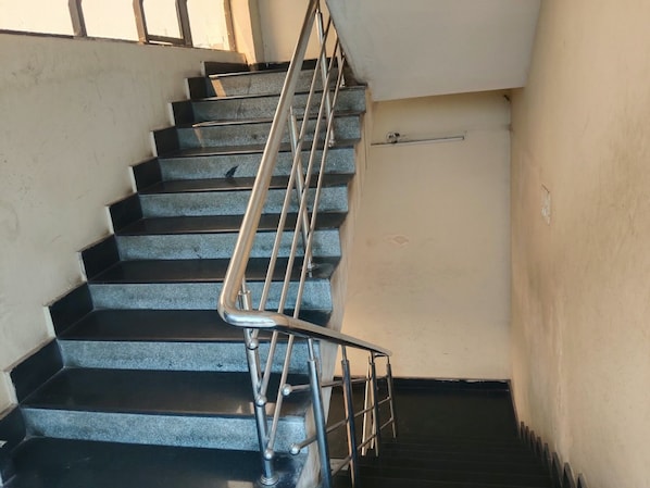 Una escalera con barandas metálicas y una baranda en el lado izquierdo, que conduce a un piso superior.