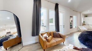 A modern living room with a sofa, a large mirror, and a view of the outside. - Rodeo House Downtown Houston (Houston)