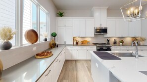 A modern kitchen with white cabinetry, a stainless steel range, and a large window. - Rodeo House Downtown Houston (Houston)