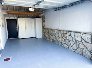 Zona interior àmplia amb paret de pedra i una porta que dona a una altra estança.