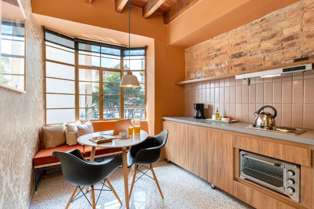 A compact kitchen with a built-in oven, a window with a view, and a seating area with a table and chairs.