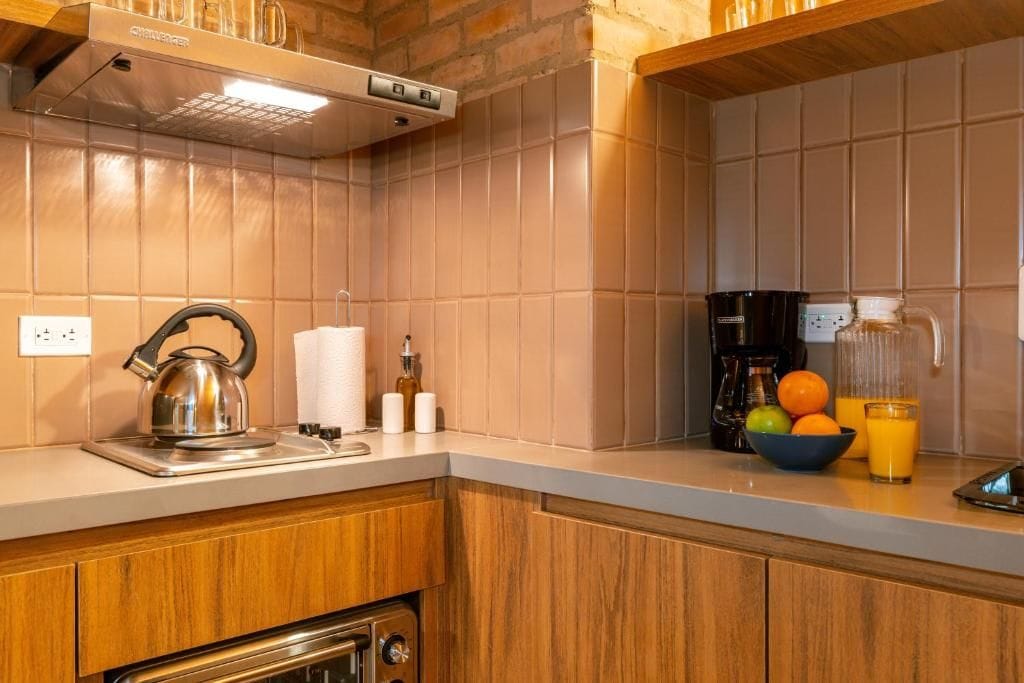 A kitchen with a kettle, a coffee maker, and a bowl of fruit.