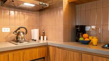 A kitchen with a kettle, a coffee maker, and a bowl of fruit.