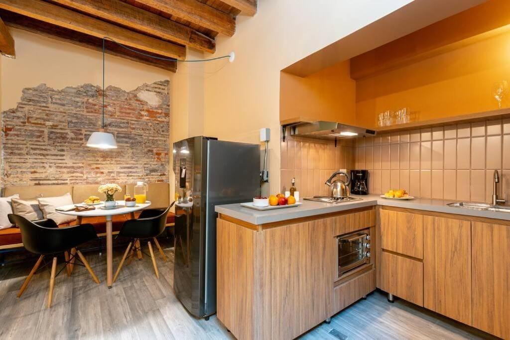 A modern kitchen with a central island, wooden cabinets, and a stone wall.