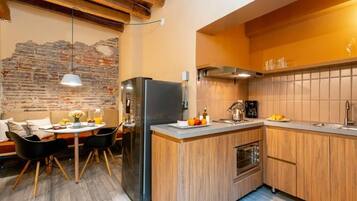 A modern kitchen with a central island, wooden cabinets, and a stone wall.