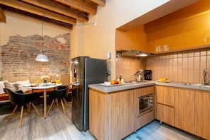 A modern kitchen with a central island, wooden cabinets, and a stone wall. - Casa Avenida Jimenez (Bogotá)