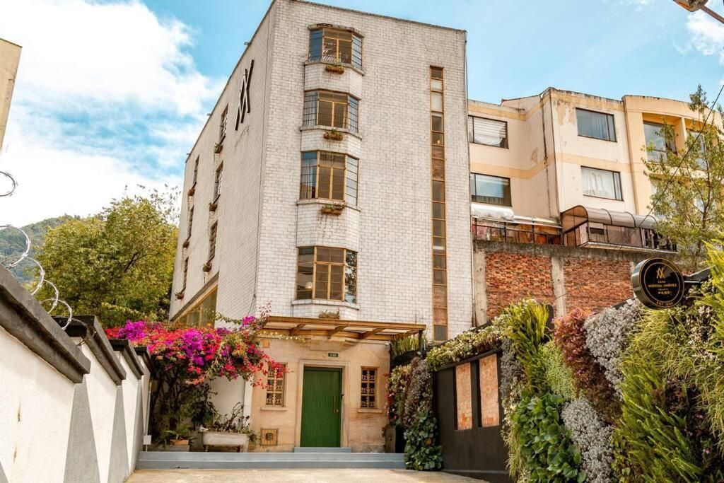 Ein mehrstöckiges Gebäude mit einer grünen Tür, einer Ziegel-Fassade und einem Balkon mit Pflanzen.