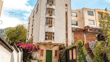Ein mehrstöckiges Gebäude mit einer grünen Tür, einer Ziegel-Fassade und einem Balkon mit Pflanzen.