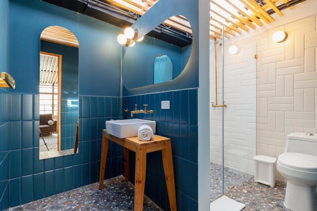 Ein Badezimmer mit blauen Wänden, einem hölzernen Hocker mit Waschbecken und einer weißen Toilette.