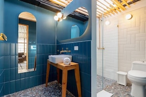 Ein Badezimmer mit blauen Wänden, einem hölzernen Hocker mit Waschbecken und einer weißen Toilette.