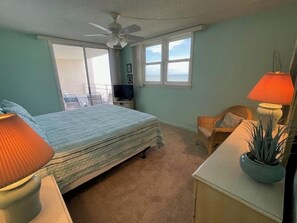 A bedroom with a bed, a chair, a desk, a television, and a window with a view. - East Wind #3030 Oceanfront Traffic Free Beach 2/2 (Ponce Inlet)