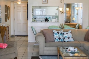 A living room with a sofa, a coffee table, and a dining area with chairs. - East Wind #3030 Oceanfront Traffic Free Beach 2/2 (Ponce Inlet)