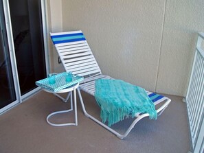 A balcony with a white chair and a small table, both with blue and white striped cushions. - East Wind #3030 Oceanfront Traffic Free Beach 2/2 (Ponce Inlet)