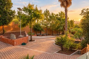A paved courtyard with brick pathways, surrounded by trees and a brick wall.
