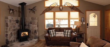 Sink into the leather sofa by your own wood-burning stove, where rustic decor and sunlit windows create a cozy mountain retreat.