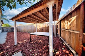 A covered outdoor area with a table and a wooden fence. - I-5 Getaway, Sleek & Spacious. All Fees included (Stockton)