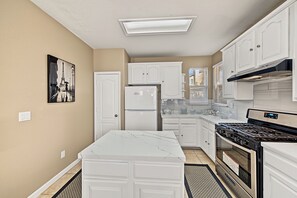 A kitchen with white cabinets, a refrigerator, a stove, and a microwave. - I-5 Getaway, Sleek & Spacious. All Fees included (Stockton)