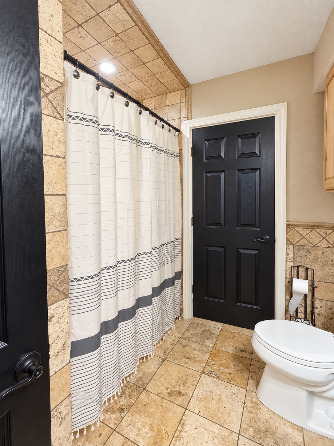 Ein Badezimmer mit Duschvorhang, Toilette und Tür.