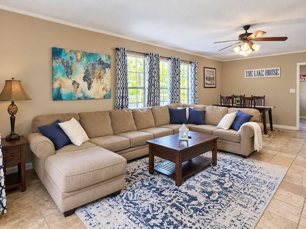 A living room with a sectional sofa, a coffee table, a lamp, and a world map painting. - (Many)