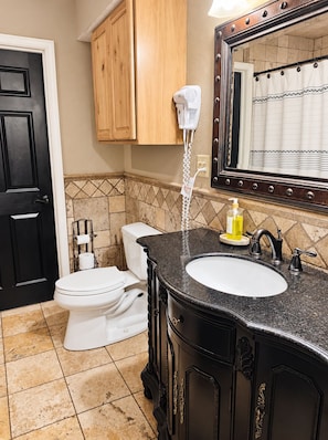 A bathroom with a toilet, sink, and a hairdryer mounted on the wall. - (Many)