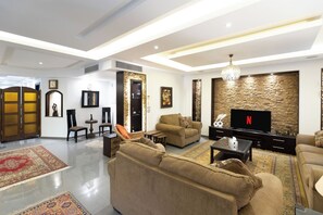 A modern living room with a sofa set, a television, and a decorative wall. - SODIC Kattameya Plaza, 3-Bedroom, 230 m² Family Apartment, 3 Pools in New Cairo (New Cairo)