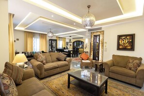 A spacious living room with two sofas, a coffee table, and a dining area in the background. - SODIC Kattameya Plaza, 3-Bedroom, 230 m² Family Apartment, 3 Pools in New Cairo (New Cairo)