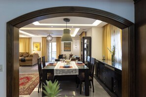 A dining area with a table set for four, surrounded by chairs, with a chandelier above. - SODIC Kattameya Plaza, 3-Bedroom, 230 m² Family Apartment, 3 Pools in New Cairo (New Cairo)