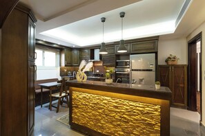 A modern kitchen with dark wood cabinets, a central island with a golden textured backsplash, and stainless steel appliances. - SODIC Kattameya Plaza, 3-Bedroom, 230 m² Family Apartment, 3 Pools in New Cairo (New Cairo)