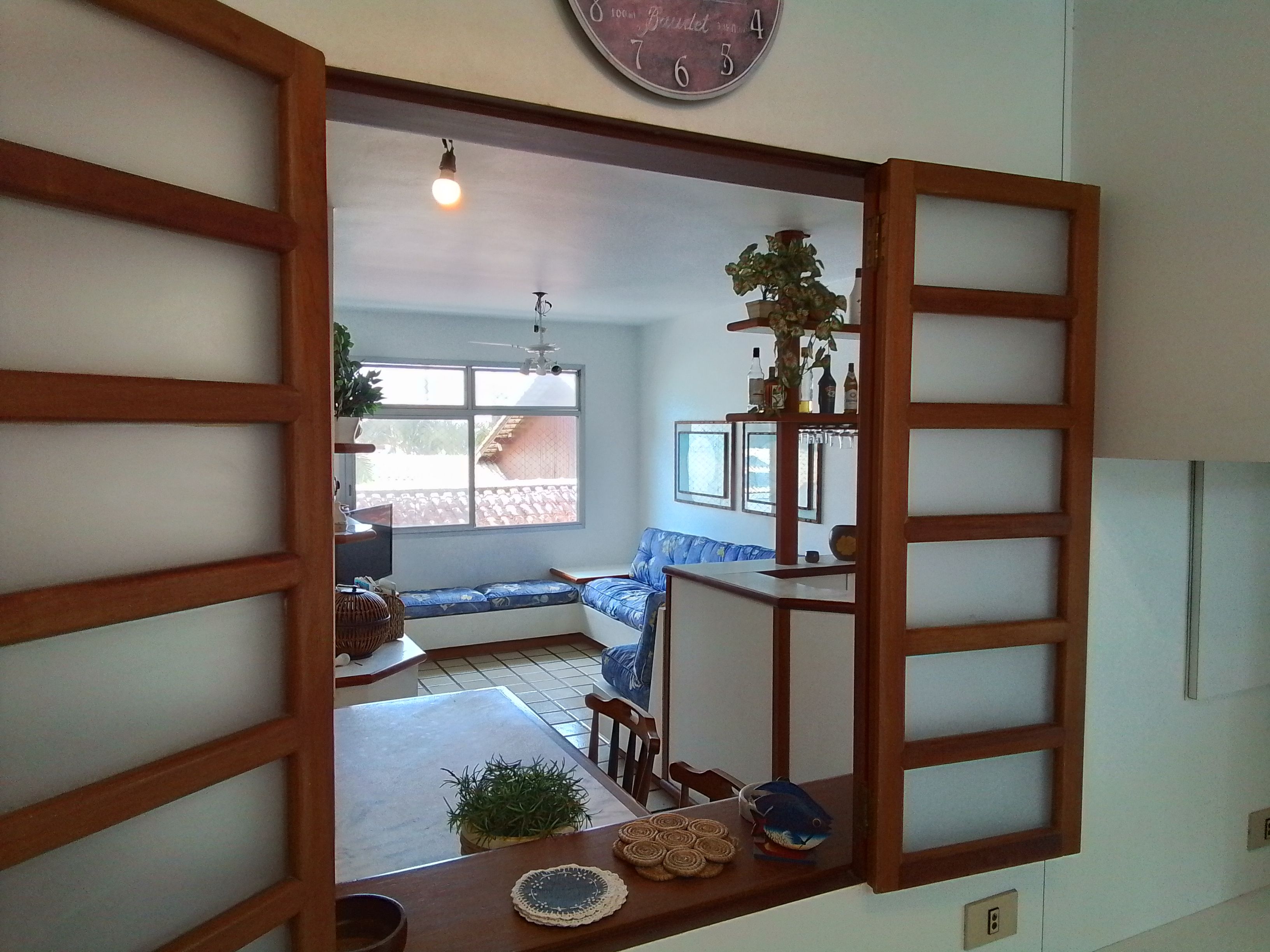 Een kamer met een houten scheiding, een bank, een klein tafeltje met een visdecoratie en een plafondventilator.