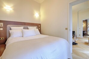 Een hotelkamer met een groot bed, twee wandlampen en een houten hoofdeinde.