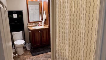 A bathroom with a toilet, sink, mirror, and shower curtain.