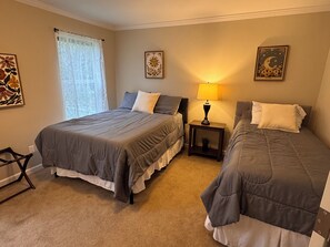 Een slaapkamer met twee bedden, een nachtkastje met een lamp en decoratieve muurkunst.
