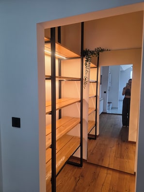 Un pasillo con suelo de madera y una estantería metálica.