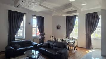 A modern living room with a sectional sofa, a glass coffee table, and a dining area with a table and chairs.