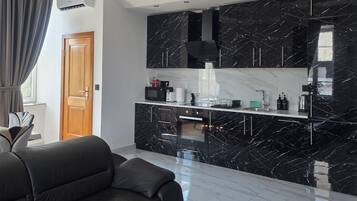 A modern kitchen with black marble countertops and a built-in oven.