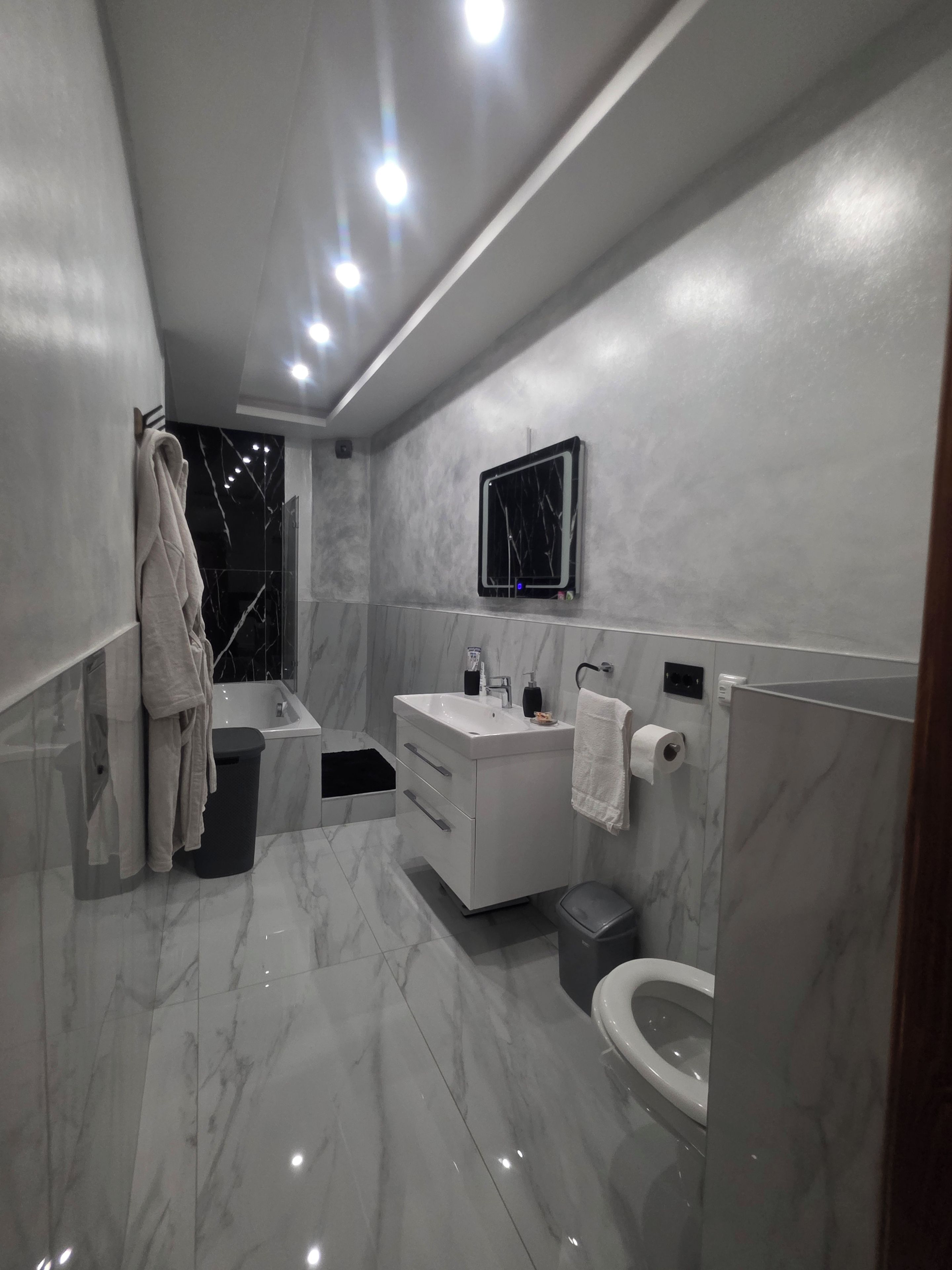 A modern bathroom with a vanity, toilet, and bathtub.