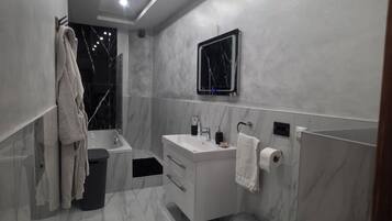 A modern bathroom with a vanity, toilet, and bathtub.