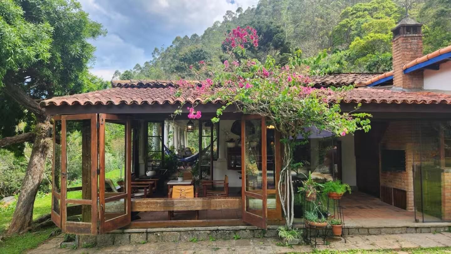 A wooden structure with a tiled roof, a hammock, and potted plants.