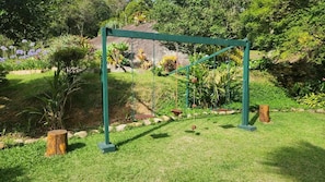 A garden with a swing set, surrounded by various plants and trees. - Sítio Duncan (Teresópolis)
