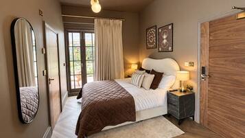 Een slaapkamer met een bed, nachtkastjes, een spiegel en een deur.
