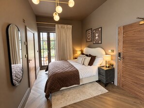Een slaapkamer met een bed, nachtkastjes, een spiegel en een deur.