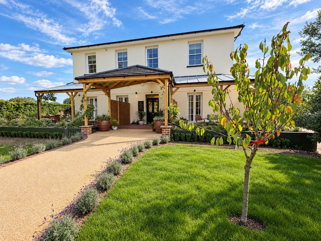 A two-story house with a covered porch, a gravel driveway, and a well-maintained lawn.